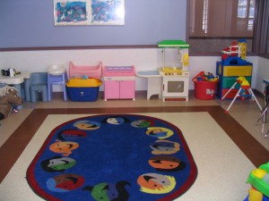 Shelter playroom with a oval rug in the middle and lots of toys to play with.