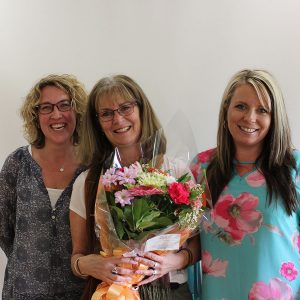 Lynette, Norah and Stacey smiling standing side by side as Norah is congratulated for her ten years of service award.