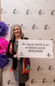 Norah Kennedy holding a sign that reads an equal world is an enabled world at the 2020 International Women's Day Celebration Luncheon.