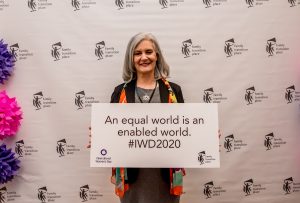 Norah Kennedy holding a sign that reads an equal world is an enabled world at the 2020 International Women's Day Celebration Luncheon.