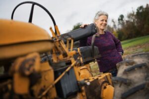 Woman standing with hand on tractor smiling.