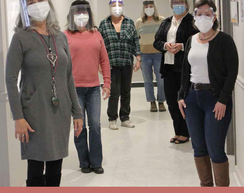 Six Family Transition Place staff standing socially distanced in hallway with face masks and face shields on.