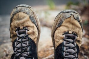 Toes of a pair of well worn hiking boots with a woodsy background.