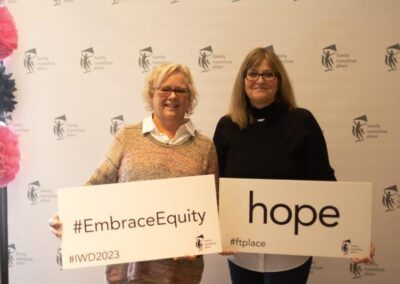 Guests from March 8, 2023 International Women's Day Celebration Luncheon fundraising event holding embrace equity and hope signs.