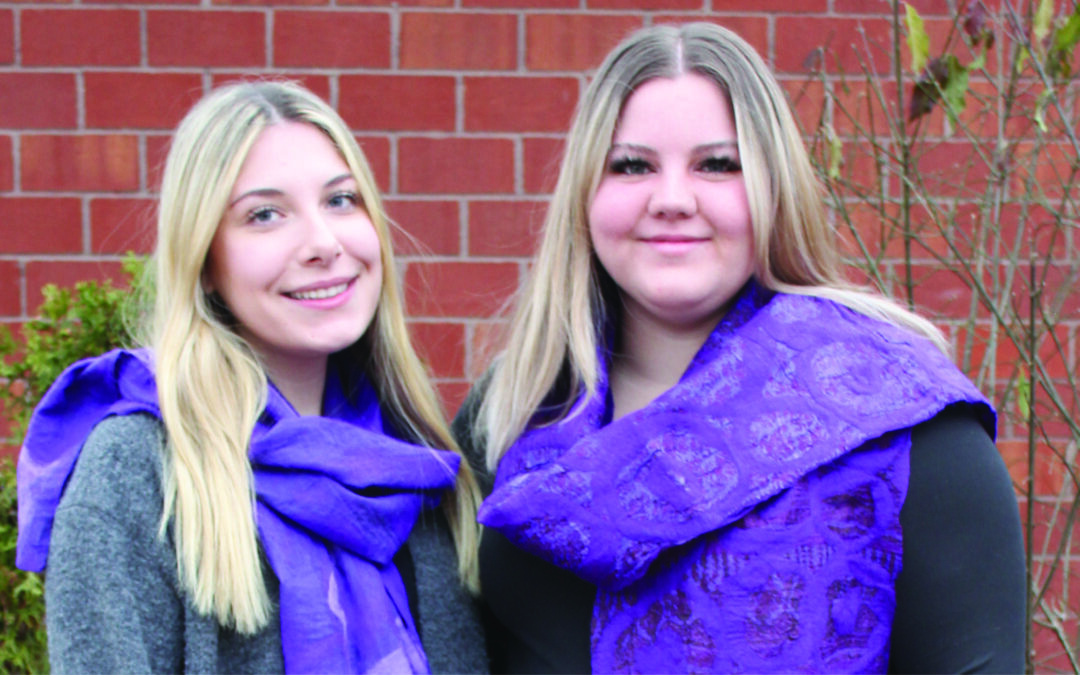 Family Transition Place staff member Brie and Madysyn wearing Wrapped in Courage purple scarves outside in front of building