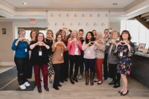 FTP staff and volunteers doing heart hand pose in front of media wall at 2024 International Women's Day Celebration Event