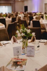 Table setting featuring flowers from Orangeville Flowers and Celebrating Women magazine at 2024 International Women's Day Celebration Event